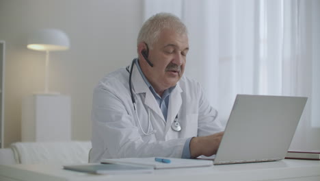 online-appointment-with-pediatrician-or-therapist-male-doctor-is-working-remotely-from-his-office-using-laptop-with-video-calling